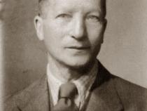 Passfoto Josef David Wolf, frontal. Josef trägt Anzug, weißes Hemd und Krawatte